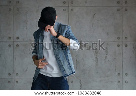 Teenager boy denim jacket and white sweater dancing hip-hop with baseball cap. Dynamics and plastic movement of modern dance. Youth fashion. Man is unrecognizable