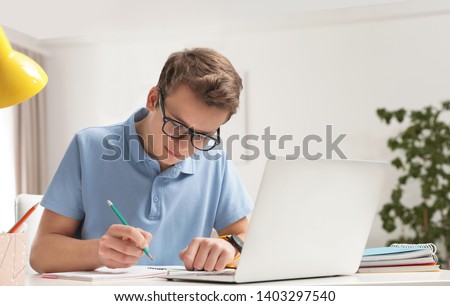 Teenager boy doing his homework at desk indoors