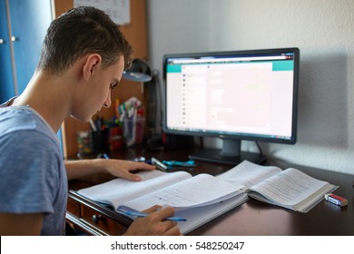 Teenager boy doing homework on his desk at home
