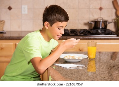 Teenager Boy Eating Cereal Drinking Orange Juice For Breakfast 