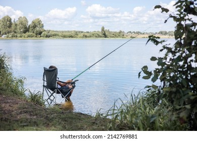 Teenager boy fishing with rods in calm river. Slow life in countryside.
