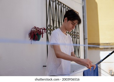 Teenager Boy Hanging Out Clean Clothes At Home