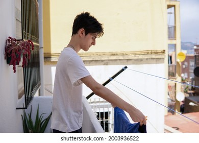 Teenager Boy Hanging Out Clean Clothes At Home