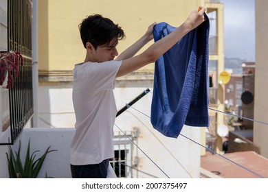 Teenager Boy Hanging Out Clean Clothes At Home