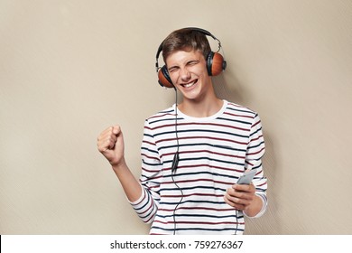 Teenager Boy With Headphones And Mobile Phone Listening To Music On Color Background