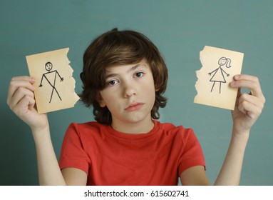 teenager boy hold mom and dad drawing in two torn paper pieces as a symbol of divorce close up sad portrait