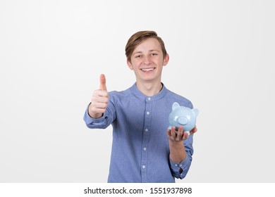 Teenager Boy Holding Piggy Bank  With Thumb Up Signs Over White Background. Financial Education Savings Concept.