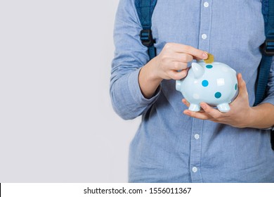 Teenager Boy Holding Piggy Bank Putting Euro Coins Inside Over White Background. Financial Education Savings Concept.