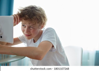 Teenager Boy Sits Looking In The Mirror And Pressing Pimples, Transitional Age Concept. 14-16 Years Old