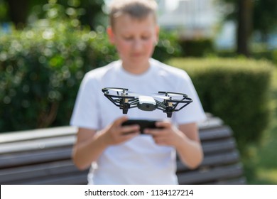 A teenager boy starts a quadrocopter from a smartphone and takes a nature shoot for his video blog. Flying robot drone. Robotics and programming. STEM education. - Powered by Shutterstock