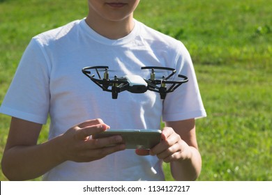 A teenager boy starts a quadrocopter from a smartphone and takes a nature shoot for his video blog. Flying robot drone. Robotics and programming. STEM education. - Powered by Shutterstock