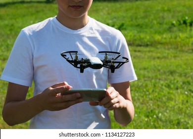 A teenager boy starts a quadrocopter from a smartphone and takes a nature shoot for his video blog. Flying robot drone. Robotics and programming. STEM education. - Powered by Shutterstock