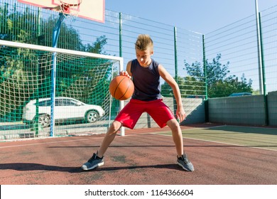 Teenager boy street basketball player on the city basketball court.