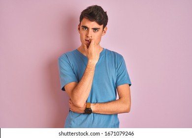 Teenager Boy Wearing Casual T-shirt Standing Over Blue Isolated Background Looking Stressed And Nervous With Hands On Mouth Biting Nails. Anxiety Problem.