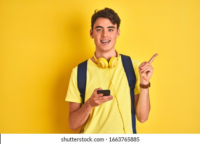 Teenager boy wearing headphones and using smartphone over isolated background very happy pointing with hand and finger to the side - Powered by Shutterstock