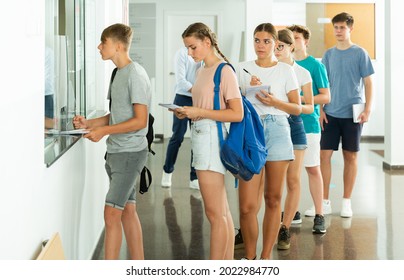 Teenager boys and girls standing in line in school's hallway