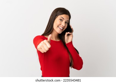 Teenager Brazilian girl using mobile phone over isolated white background with thumbs up because something good has happened - Powered by Shutterstock