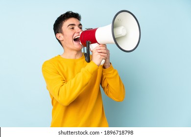Teenager caucasian handsome man isolated on purple background shouting through a megaphone