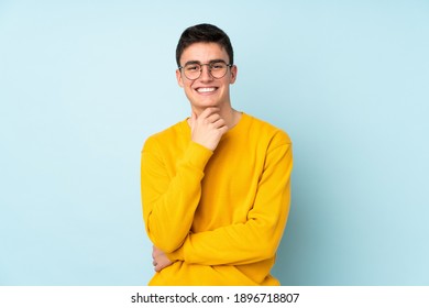 Teenager caucasian handsome man isolated on purple background with glasses and smiling