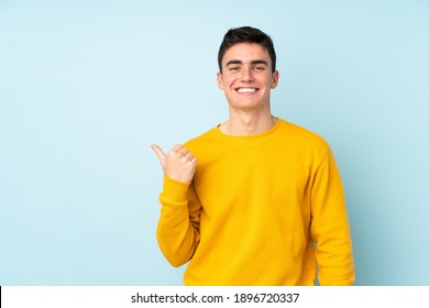Teenager, vorsichtiger, gut aussehender Mann einzeln auf violettem Hintergrund, der auf die Seite zeigt, um ein Produkt zu präsentieren