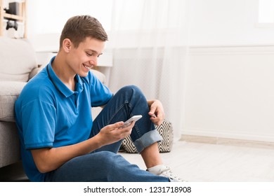 Teenager Checking Social Media On Smartphone At Home Sitting On Floor, Copy Space