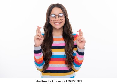 Teenager child holding fingers crossed for good luck. Portrait of cheerful girl prays and hopes dreams come true, crosses fingers for good luck, closes eyes, isolated on white studio background.