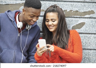 Teenager Couple Sharing Text Message On Mobile Phone