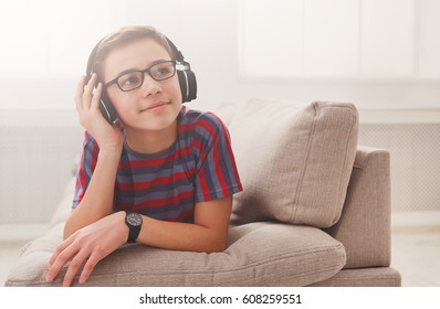 Teenager Enjoy Music - Portrait Of Dreamy Kid In Headphones While Lying On Sofa Indoors. Relax Time - Teenage Boy Listen To Music On Couch At Home