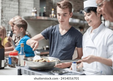 Teenager and female chef cooking together - Powered by Shutterstock