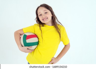 A teenager girl in a bright yellow t-shirt holds a volleyball ball in her hand and smiles on a white background. Studio photo. - Powered by Shutterstock