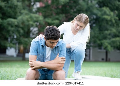 Teenager Girl Consoling Sad Hispanic Boy Outdoors In A Park. Mourning, Depression And Anxiety Concept.