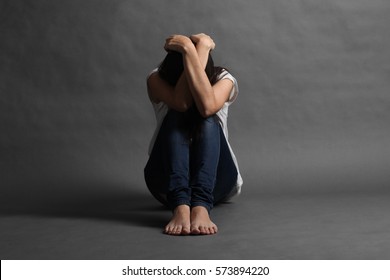 Teenager girl with depression sitting alone on the floor in the dark room.