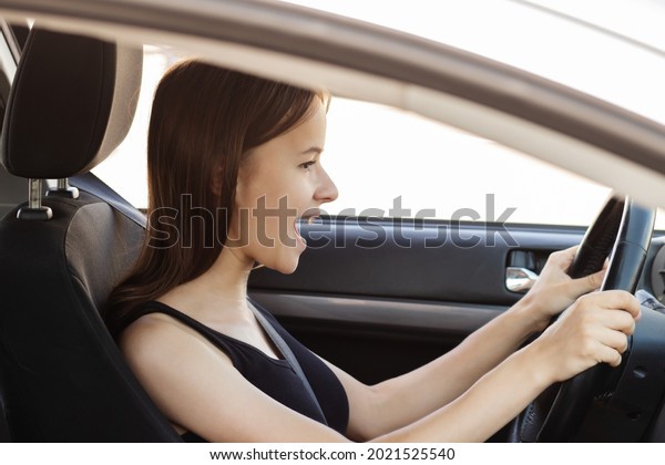 teenager girl is driving a car\
for the first time,is afraid to drive a car, waves her hands and\
shouts
