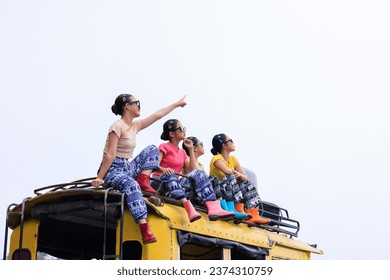  teenager girl friends group sitting on the roof of yellow a minibus, chiamg mai thailand, amazing travel tourist in the rain season concept,