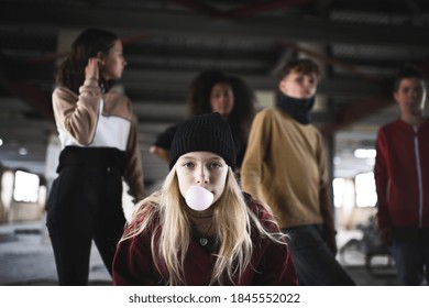 Teenager girl with friends standing indoors in abandoned building, making bubble gum. - Shutterstock ID 1845552022