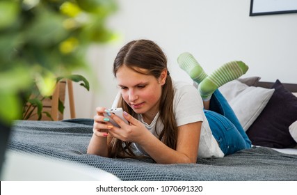 Teenager girl have fun with smartphone laying on the bed at home - Powered by Shutterstock