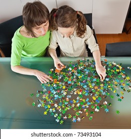 Teenager girl and her mother doing a puzzle at home