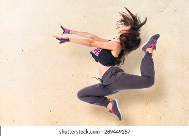 Teenager girl jumping in hip hop style over textured background 