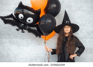 Teenager Girl With Long Hair In Witch Costume And Balloons With Bat Going To Halloween Kids Party