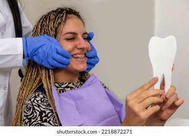 Teenager Girl Looking At Her Braces And Teeth In The Mirror At Dentist's Office