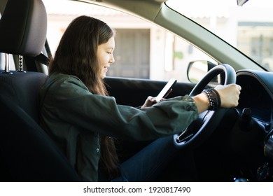 Teenager Girl Looking At Her Smartphone And Texting While Driving A Car. Bad Teen Driver Not Paying Attention To The Road And Traffic