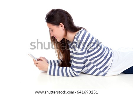 Teenager girl lying down looking the mobile isolated on a white background