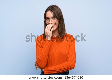 Teenager girl over blue wall smiling a lot