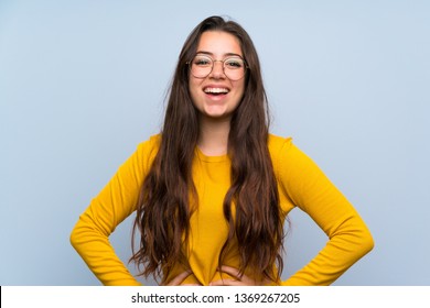 Teenager girl over isolated blue wall laughing