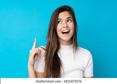 Teenagermädchen auf einzeln blauem Hintergrund, das die Lösung beim Heben eines Fingers nach oben erkennen möchte