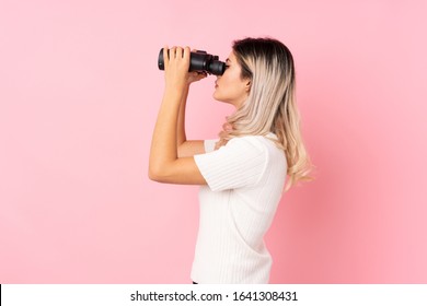 Teenager Girl Over Isolated Pink Background With Black Binoculars