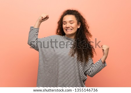 Teenager girl over pink wall celebrating a victory