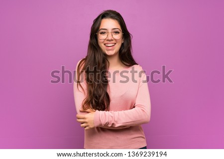 Teenager girl over purple wall keeping the arms crossed in frontal position