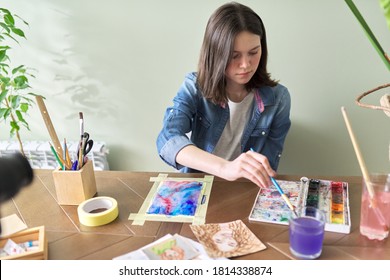 Teenager girl painting with watercolors, sitting at home at the table. Art, education, creativity, teenage hobbies