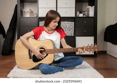 teenager girl playing guitar at home in teen room, teen girl enjoying music, girl strumming guitar on the floor